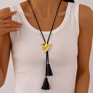 Detailed view of a golden bird pendant with black tassels and leather cord on a model