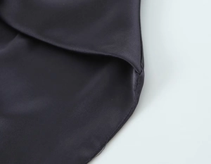 Détail de la texture satinée noire et des coutures précises de l'ourlet sur le vêtement