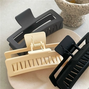 Macro shot of large matte rectangular hair claws in black, beige, and dark grey tones