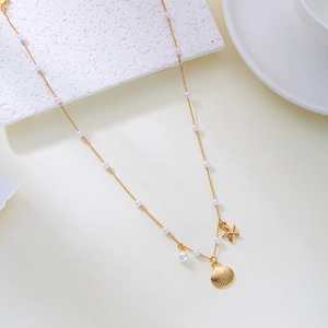 Détail du collier doré avec pendentifs étoile de mer, coquillage et perles blanches