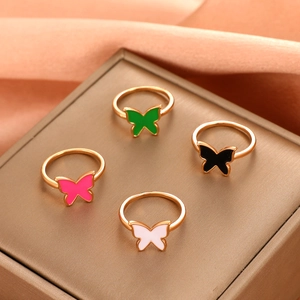 Detailed view of four golden butterfly rings in green black pink and white enamel colors