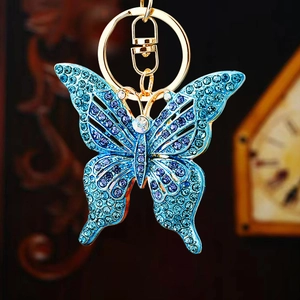 Detailed close-up of blue rhinestone-studded butterfly keychain with golden metal ring