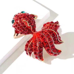 Close-up of a sparkling goldfish brooch with red crystals and green gemstone eyes