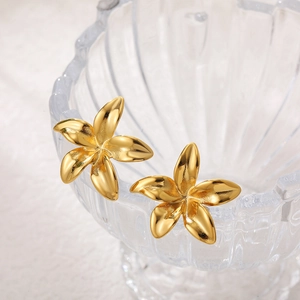 Macro shot of gold floral earrings with pearls on a textured glass bowl edge
