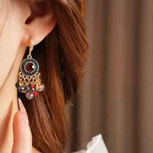 Detailaufnahme von Vintage Gold-Ohrringen mit roten Steinen und bunten Perlenanhängern