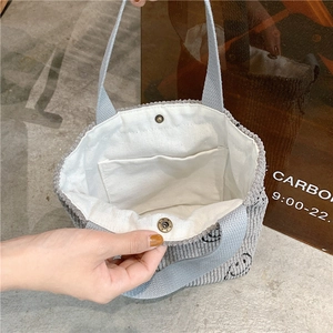 Detail of light blue corduroy handbag featuring magnetic closure and canvas inner pocket