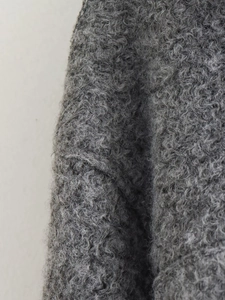 Macro shot of grey wool boucle jacket fabric with thick curly textured grain detail