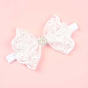 White baby lace bow headband with pearls and rhinestones on soft pink background