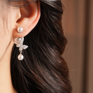 Close-up of vintage gold-plated butterfly pearl earring worn by model in warm lighting