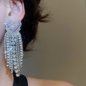 Detail of elegant silver heart tassel earrings with pink stones and dangling rhinestones