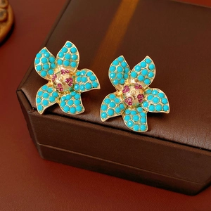 Detailed macro view of vintage flower stud earrings with teal beads and pink crystals