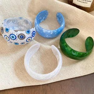 Detail of colorful resin evil eye open cuffs in marble and iridescent finishes