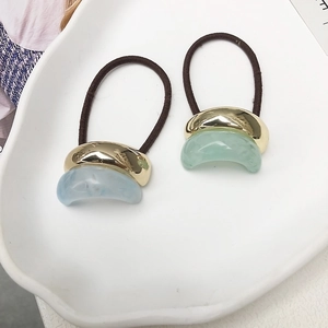 Elegant U-shaped hair ties with marble resin and gold metal plates on a ceramic tray