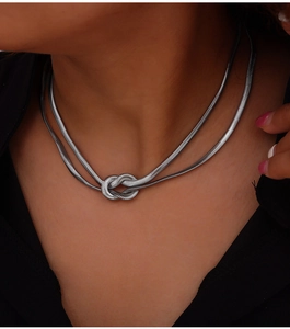 Close-up of double-layered silver snake chain necklace with a unique knot pendant design
