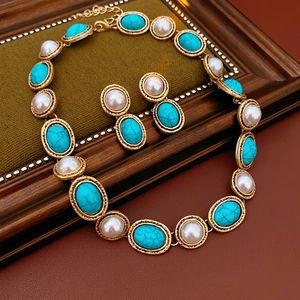 Vintage jewelry set featuring pearl and turquoise necklace and earrings on wood background