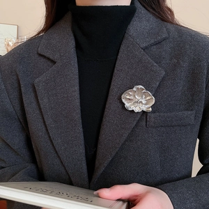Detailed shot of a silver orchid flower brooch pinned on a dark grey suit lapel