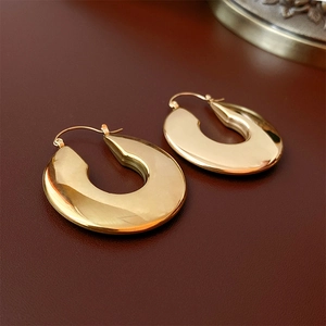 Macro shot of polished gold U-shaped hoop earrings with a sleek metallic mirror finish