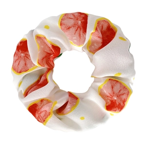 Detail of white fabric hair scrunchie with red grapefruit slice and yellow dot patterns