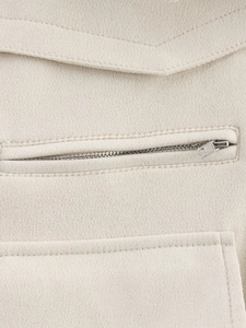 Detailed close-up of zipper pocket and stitching on cream faux suede jacket