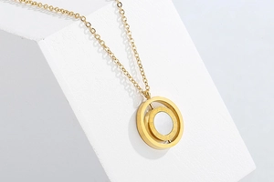 Close-up of golden necklace with circular white mother-of-pearl double ring pendant