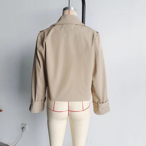 Back view of short khaki trench coat featuring buckled straps on cuffs and lapel collar