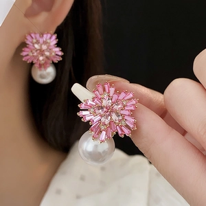 Detailed view of flower-shaped earrings with pink zircon petals and hanging pearls