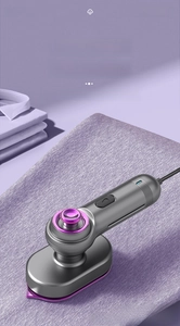 Close-up of portable garment steamer with pointed nozzle on purple fabric and white shirt