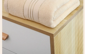 Detail of soft cotton bath towel in apricot featuring three decorative jacquard stripes