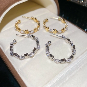 Detailed view of silver and gold C-shaped hoop earrings with sparkling star zircon stones