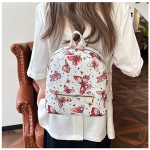 Close-up of white backpack with red butterfly pattern and golden metallic zipper