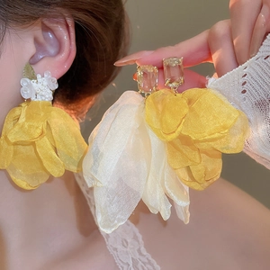 Detailed view of oversized yellow and beige chiffon flower earrings with crystal stud