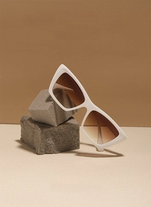 Macro shot of white cat-eye sunglasses with gradient brown lenses on stone base