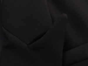 Detailed close-up showing the fine texture of black double-breasted blazer fabric