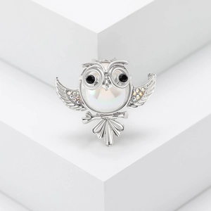 Exquisite owl brooch with pearl and colorful rhinestones on a minimalist white pedestal