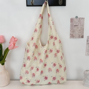 Detailed embroidery texture on a large beige canvas tote bag with pink floral patterns