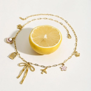 Gold stainless steel charm necklace with bow and pink shell pendants on lemon background