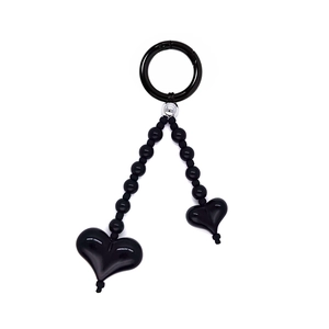 Detail of a black heart-shaped beaded charm featuring a circular ring and acrylic pendants
