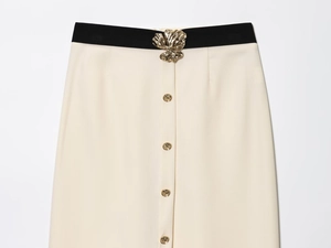 Détail de la jupe beige avec ceinture noire et boucle fleurie dorée élégante