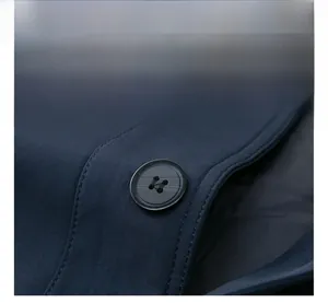 Details einer dunkelblauen Jacke mit schwarzem Knopf und feiner Nahtverarbeitung