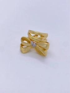 Detailed shot of 18K gold plated bow ring with brushed texture and small inset diamond