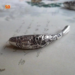 Macro shot of silver metal fish charm with detailed carving for ethnic jewelry making