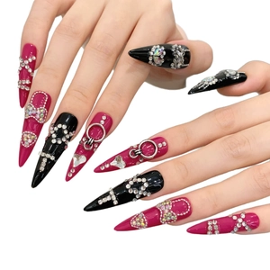 Dettaglio di unghie stiletto extra lunghe rosa e nere con decorazioni in strass
