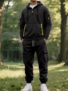 Detail of black men's hooded fleece sweatshirt with neon yellow zipper in forest setting