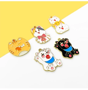 Macro view of five colorful enamel cat charms with golden borders and vibrant patterns