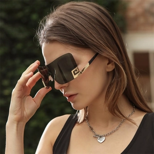 Detalle de gafas de sol cuadradas sin montura con lentes grises y patillas metálicas doradas