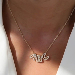 Close-up of gold plated brass necklace featuring ABC letter pendants with zircon inlay