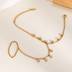 Détail de bracelet-bague en acier inoxydable doré avec zircons blancs sur support pierre