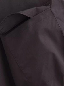 Détail macro de la texture du coton et des coutures de poche sur la veste sombre femme