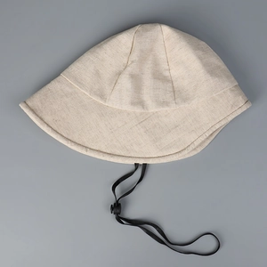Detail eines beige Fischerhuts aus Leinen mit verstellbarem schwarzem winddichtem Kinnriemen