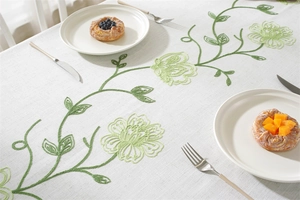 Detail of embroidered green floral patterns on a beige linen blend festive tablecloth